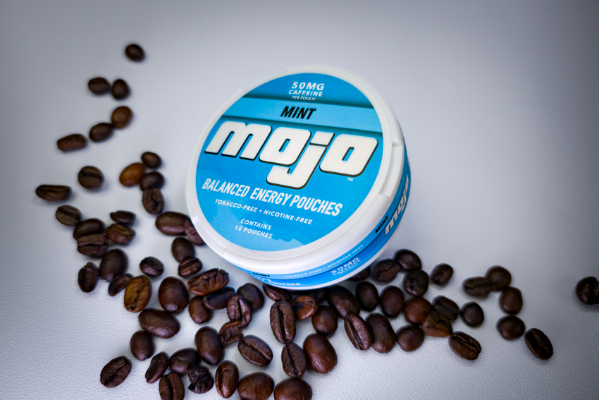 Caffeine pouch container surrounded by coffee beans