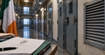 Secure prison corridor with ventilation grilles and Irish government documents in the foreground