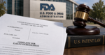 Patent documents and a court filing arranged on a desk with a federal courthouse blurred in the background